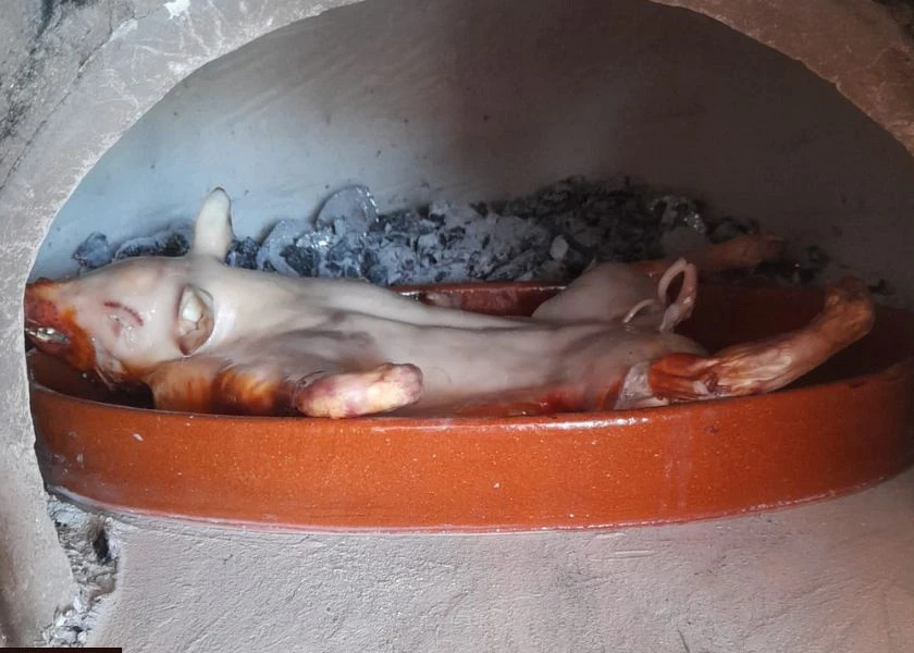 Pig on a clay spit and baking in the wood-fired oven